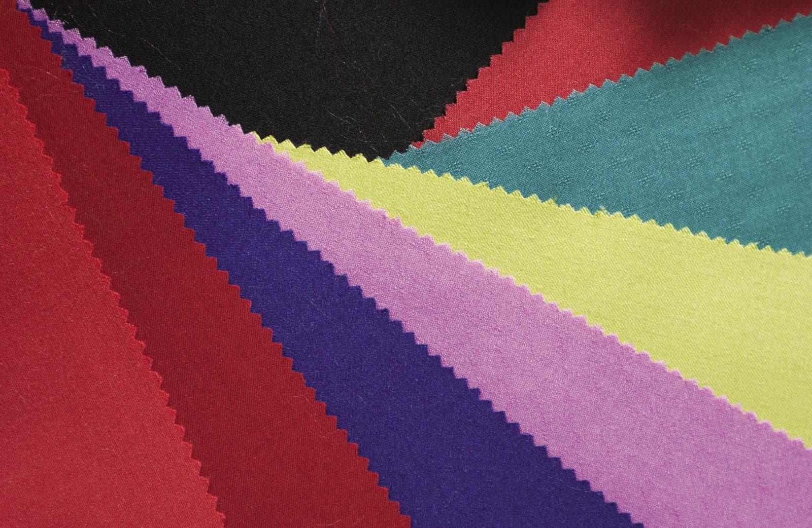 Des échantillons de tissu déployés en éventail : rouge, violet, rose, jaune, vert et noir
